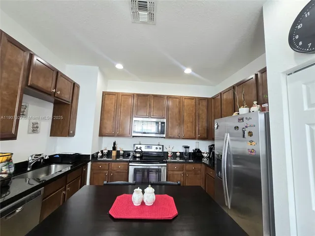 a kitchen with stainless steel appliances granite countertop a refrigerator stove and sink