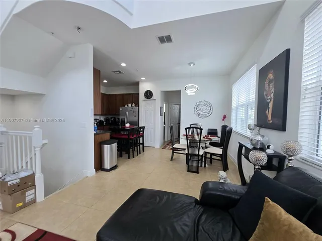 a living room with furniture kitchen view and a large window