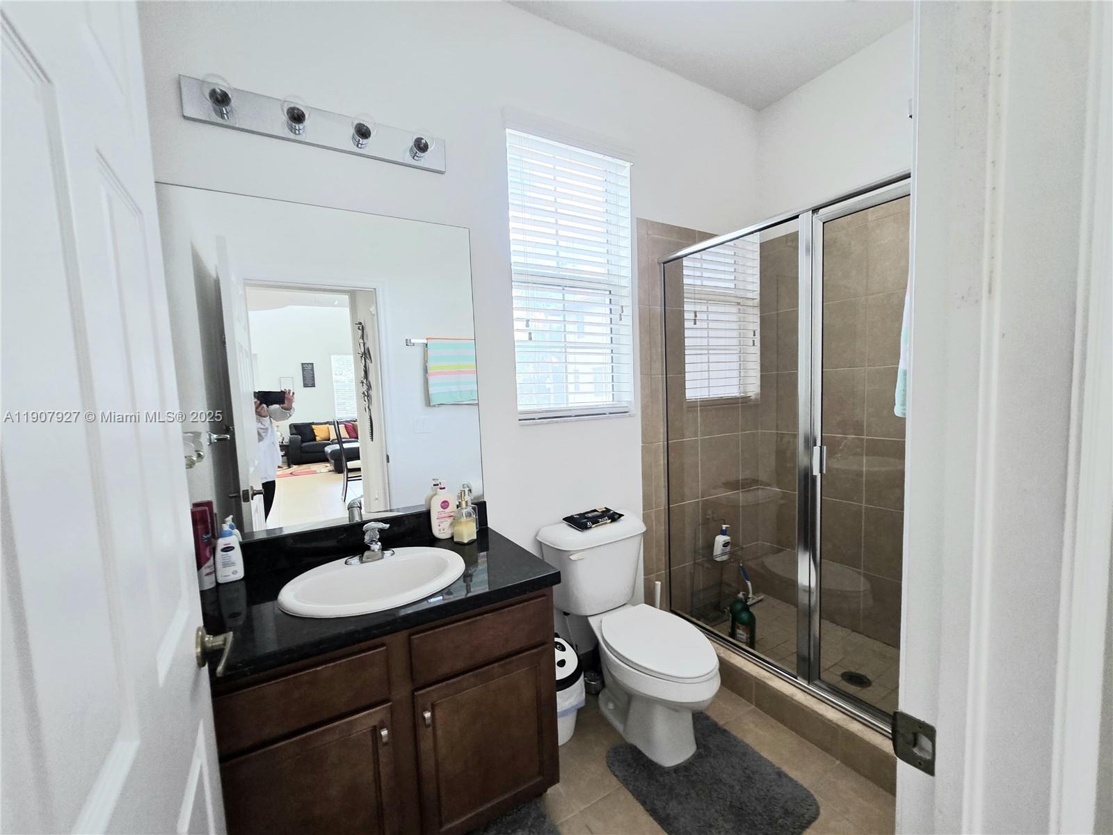 11938 Southwest 26th Court Miramar, FL 33025 - Photo 28 of 61 a bathroom with a granite countertop sink toilet a mirror and shower