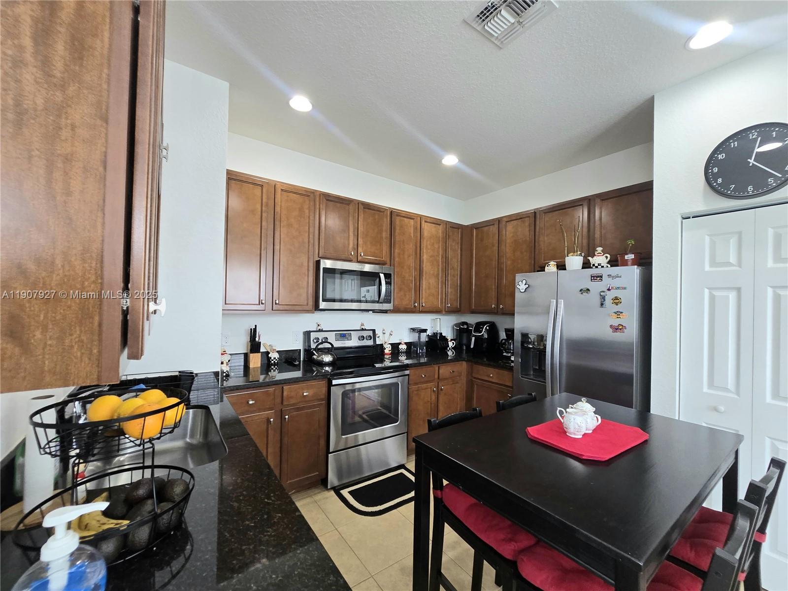 11938 Southwest 26th Court Miramar, FL 33025 - Photo 10 of 61 a kitchen with stainless steel appliances granite countertop a stove refrigerator a sink dishwasher and a dining table with wooden floor