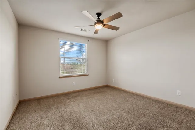 an empty room with window and ceiling fan