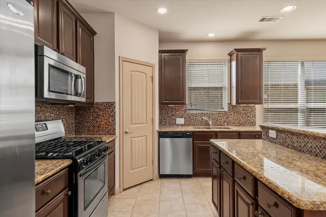 a kitchen with stainless steel appliances granite countertop a stove microwave and sink