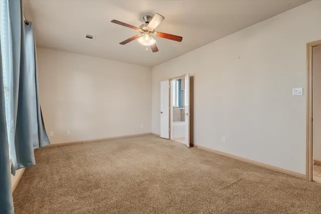 an empty room with a chandelier fan and windows