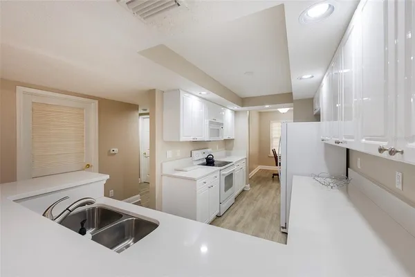 a kitchen with a sink a stove a refrigerator and white cabinets