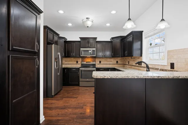 a kitchen with stainless steel appliances granite countertop a refrigerator a sink and a stove