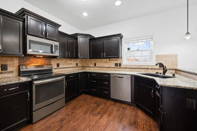 a kitchen with stainless steel appliances granite countertop a sink stove and microwave