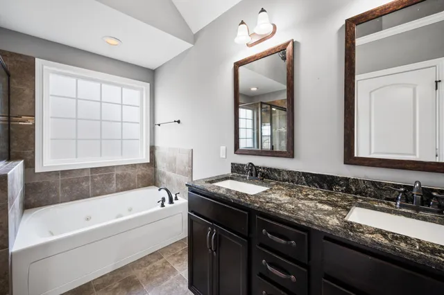 a bathroom with a granite countertop tub sink and mirror