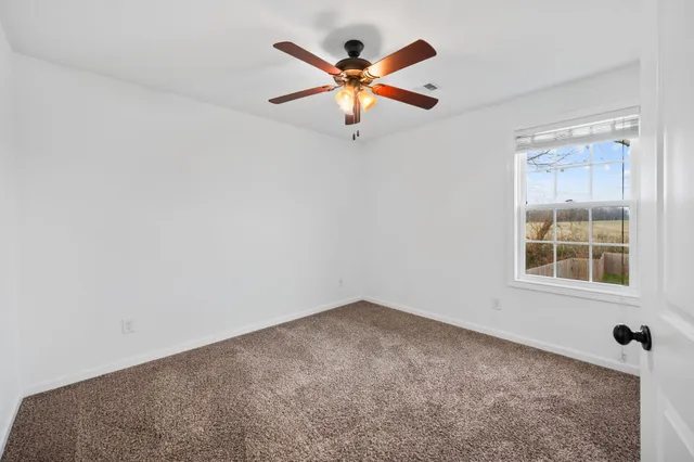 an empty room with ceiling fan and window