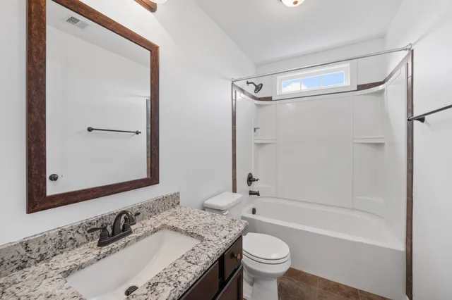 a bathroom with a granite countertop sink toilet and shower