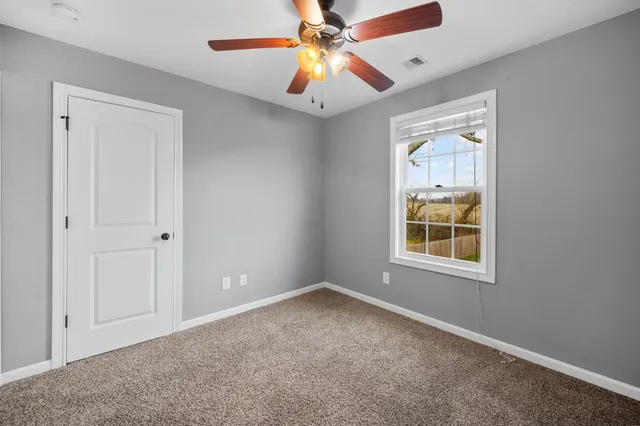 an empty room with windows and fan