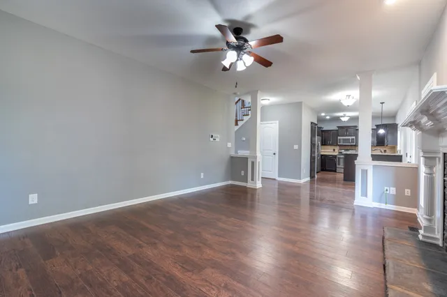 an empty room with wooden floor and a kitchen