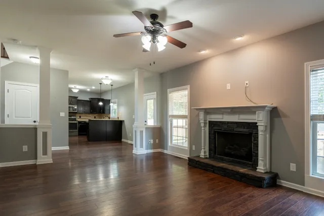 a view of an empty room with kitchen and fireplace