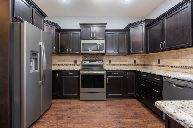 a kitchen with stainless steel appliances granite countertop wooden cabinets a stove top oven a sink and dishwasher