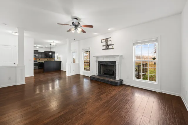a view of a livingroom with wooden floor a ceiling fan and windows