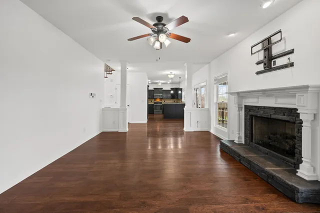 a view of a livingroom with a fireplace a ceiling fan a fireplace and windows