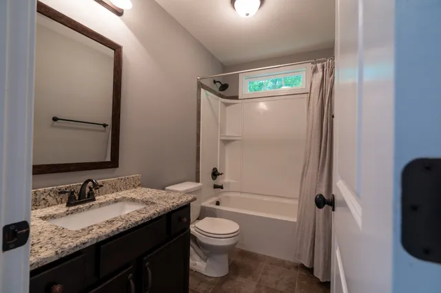 a bathroom with a granite countertop sink toilet a mirror and shower
