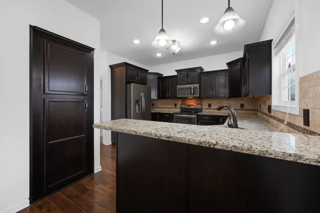 a kitchen with stainless steel appliances granite countertop a refrigerator a stove a sink and a oven with wooden floor