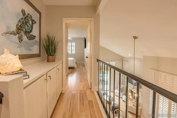 a view of a hallway with wooden floor and a bathroom