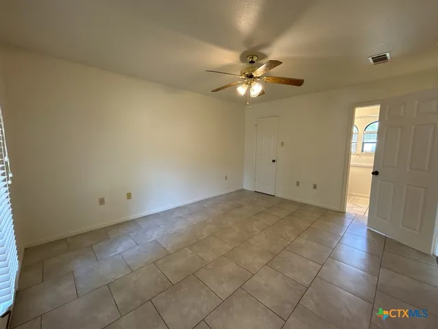 an empty room with a chandelier fan and windows