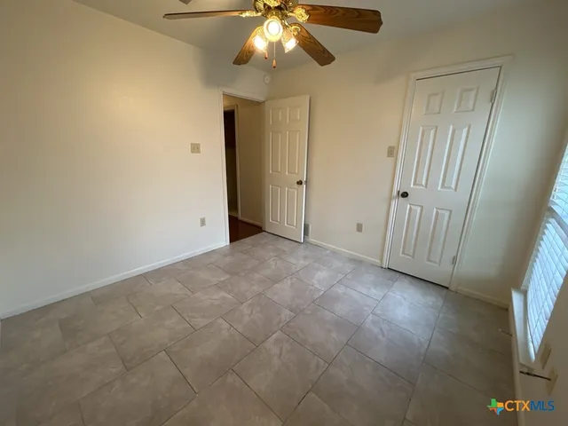 an empty room with windows and fan