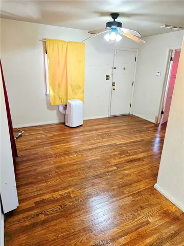 a view of an empty room with window and wooden floor