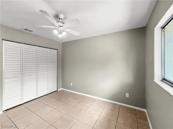 an empty room with windows and fan