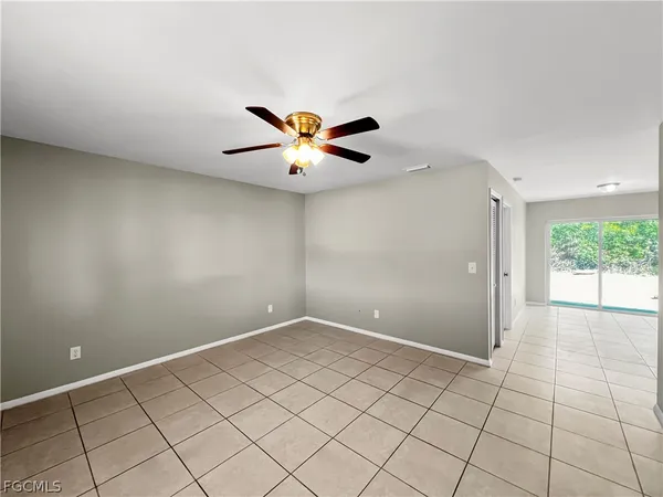 an empty room with a chandelier fan and windows