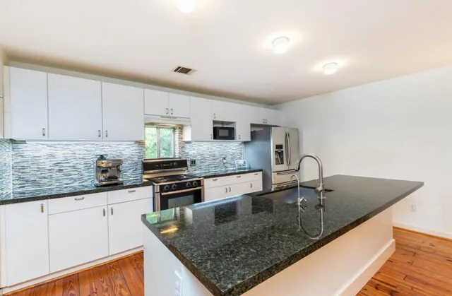a kitchen with stainless steel appliances granite countertop a sink a stove and a refrigerator