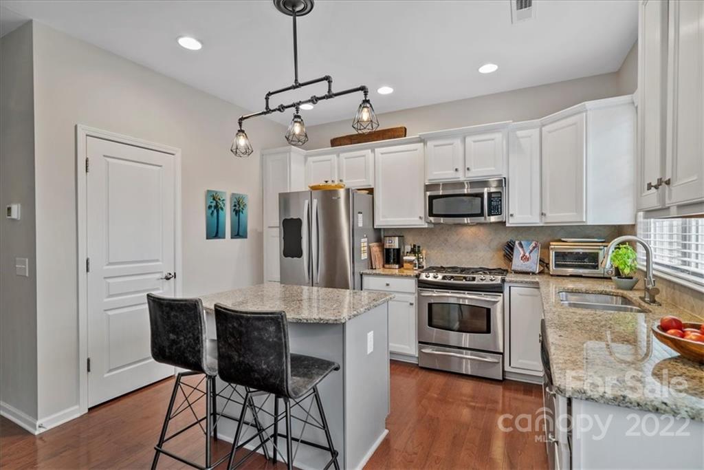 647 6th Baxter Crossing Fort Mill, SC 29708 - Photo 9 of 34 a kitchen with stainless steel appliances granite countertop a stove a sink a refrigerator a microwave a dining table and chairs with wooden floor