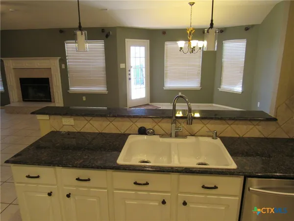 a kitchen with kitchen island granite countertop a sink a stove and cabinets