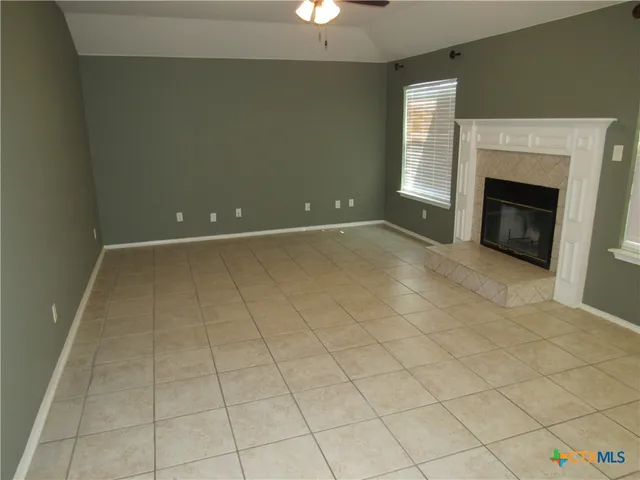 an empty room with windows and fireplace