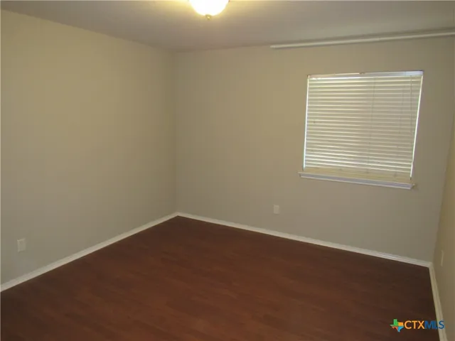 an empty room with wooden floor and a window