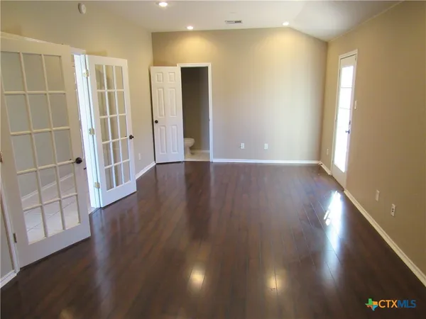 an empty room with wooden floor and windows