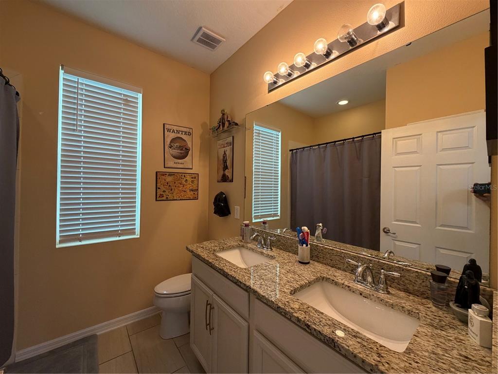 1834 Castleton Drive St. Cloud, FL 34771 - Photo 15 of 33 a bathroom with a granite countertop sink vanity mirror and a toilet