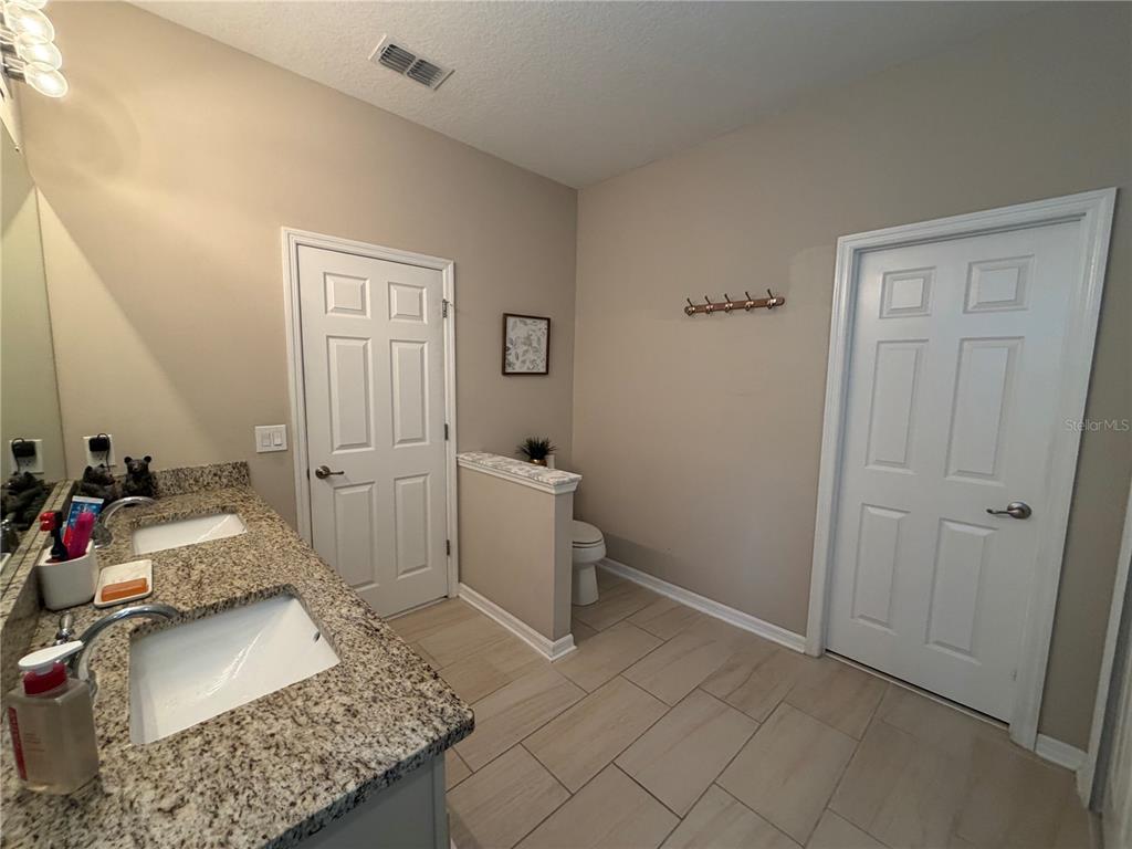 1834 Castleton Drive St. Cloud, FL 34771 - Photo 29 of 33 a bathroom with a granite countertop sink a toilet and a mirror
