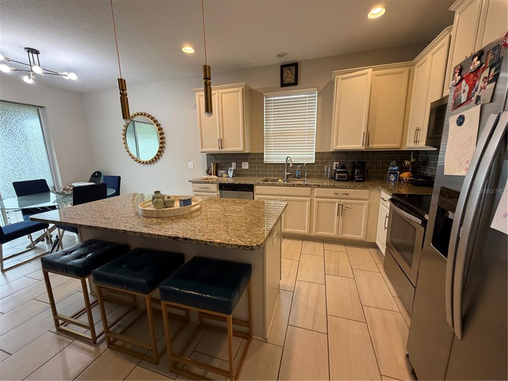 1834 Castleton Drive St. Cloud, FL 34771 - Photo 5 of 33 a kitchen with stainless steel appliances granite countertop a sink a stove a refrigerator cabinets and dining table