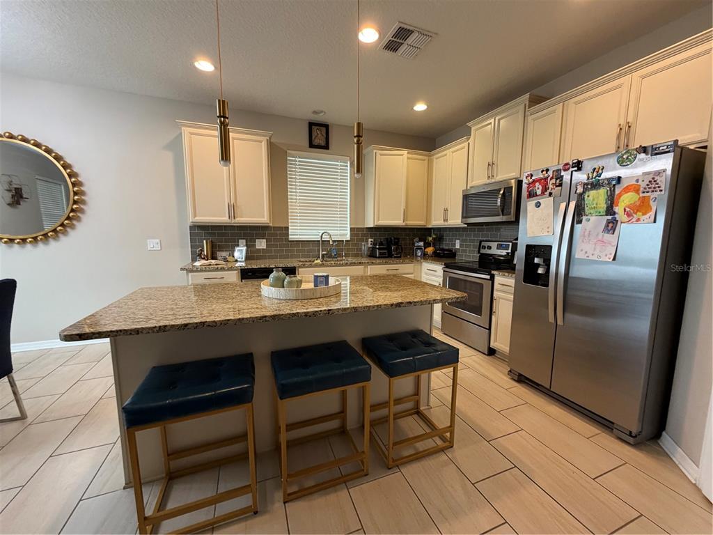 1834 Castleton Drive St. Cloud, FL 34771 - Photo 6 of 33 a kitchen with stainless steel appliances a sink a stove a refrigerator cabinets and dining table