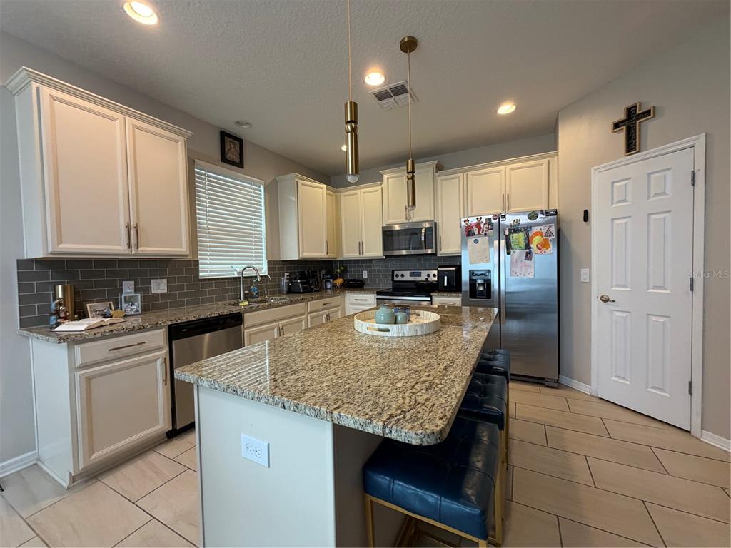 1834 Castleton Drive St. Cloud, FL 34771 - Photo 7 of 33 a kitchen with stainless steel appliances granite countertop a table chairs sink and cabinets