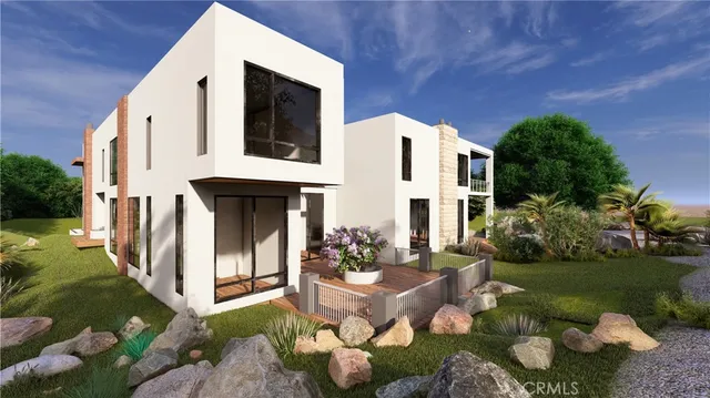 a view of a white house with a small yard and potted plants