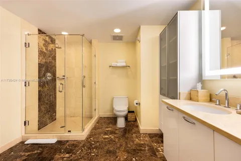 a bathroom with a granite countertop sink a toilet and shower
