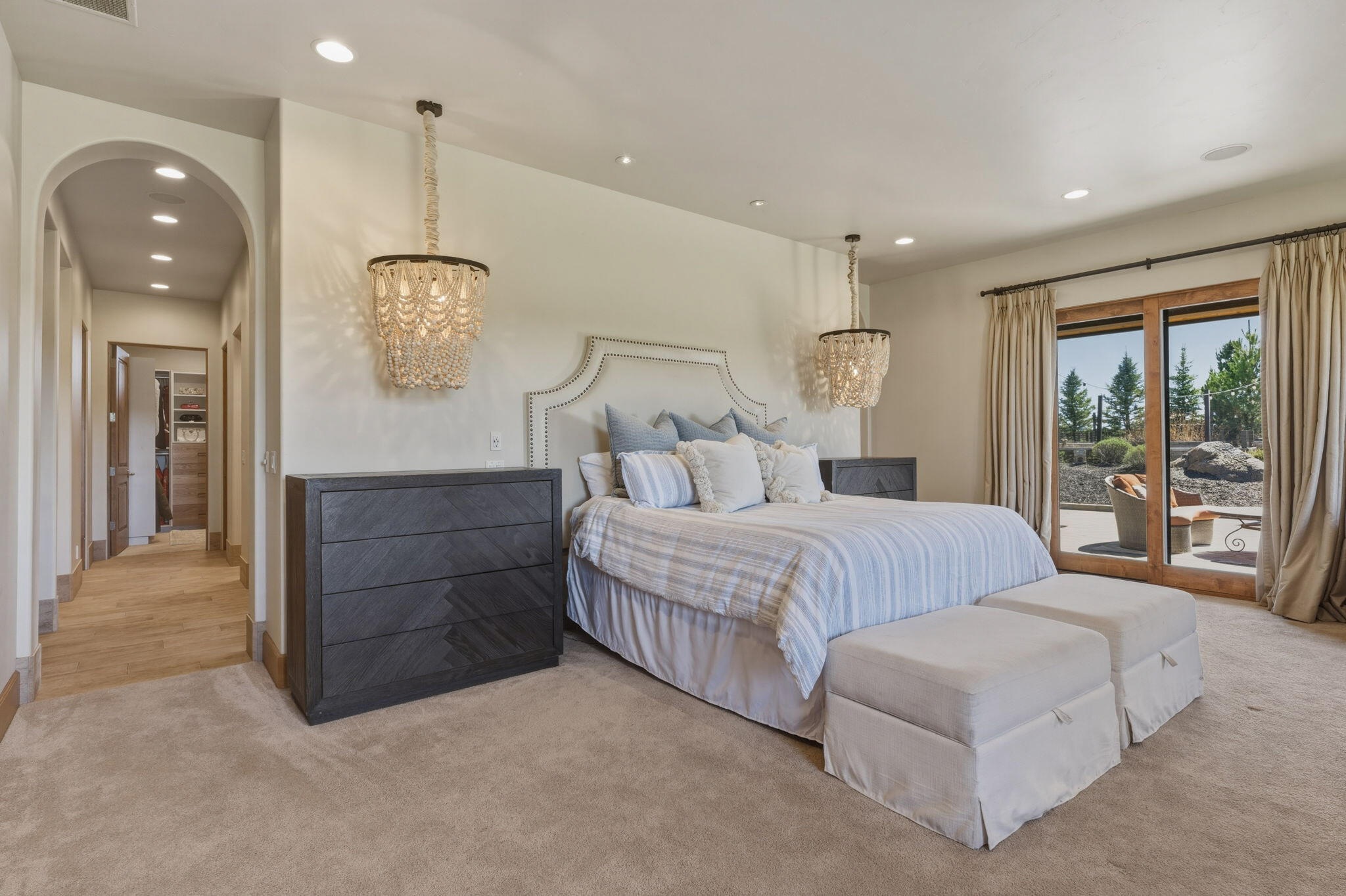 19100 Macalpine Loop Bend, OR 97702 - Photo 22 of 56 Primary ensuite with chandeliers, arched hallway, and access to private patio