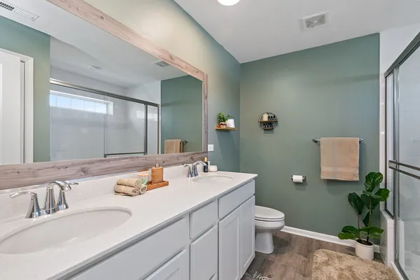 a bathroom with a double vanity sink toilet and a mirror