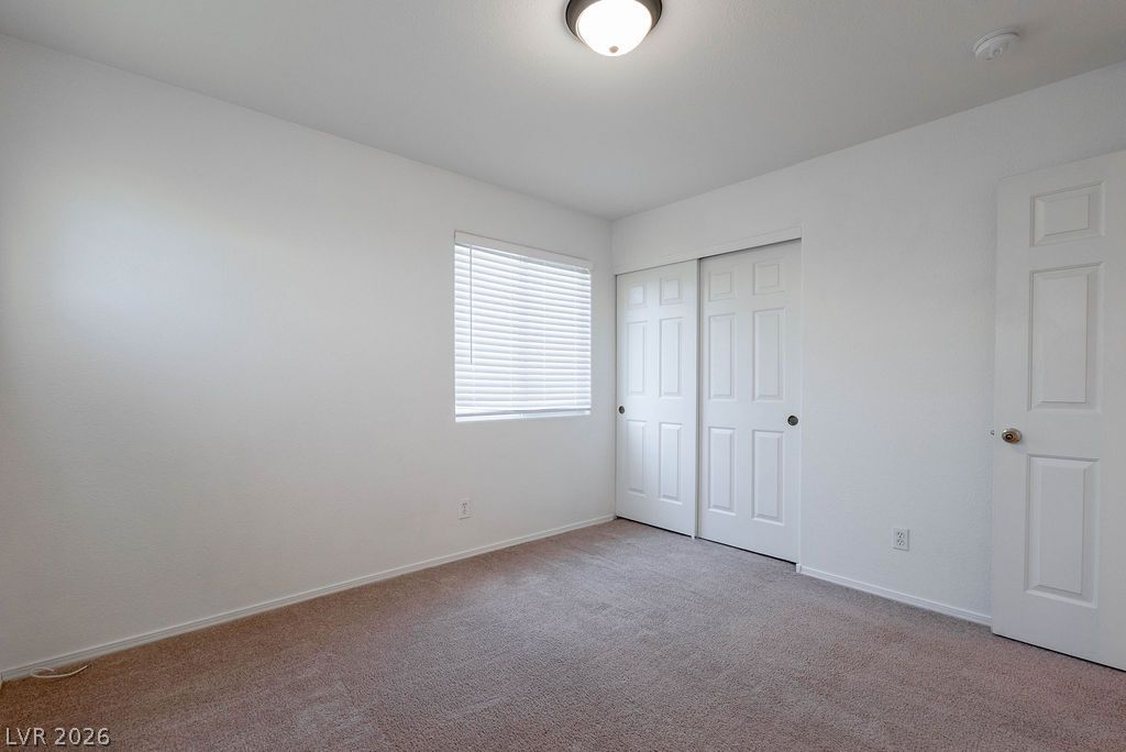 8379 Rockefeller Street Las Vegas, NV 89123 - Photo 30 of 36 A window brings natural light into this bedroom featuring wall-to-wall carpeting and sliding closet doors.