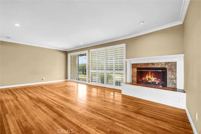 a view of an empty room with wooden floor fireplace and a window
