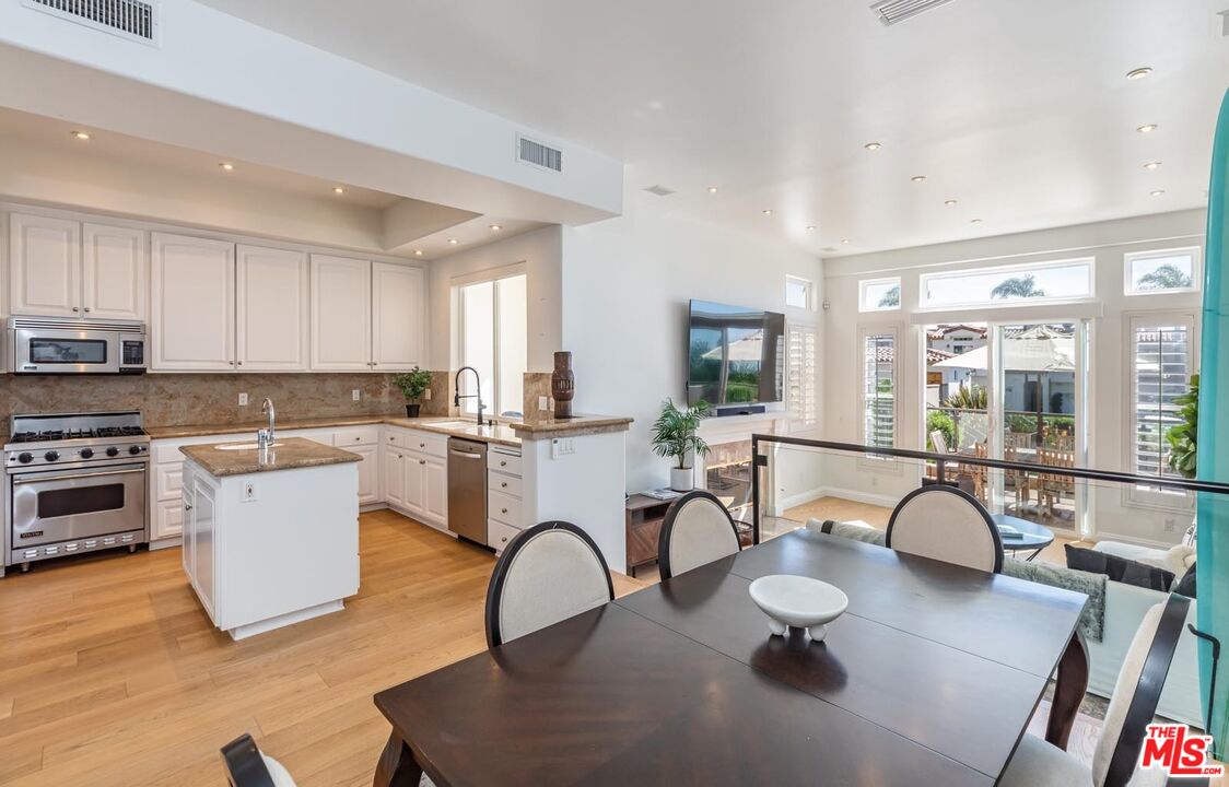 6438 Lunita Road Malibu, CA 90265 - Photo 8 of 34 a kitchen with a table chairs a sink dishwasher a stove and a dining table with wooden floor