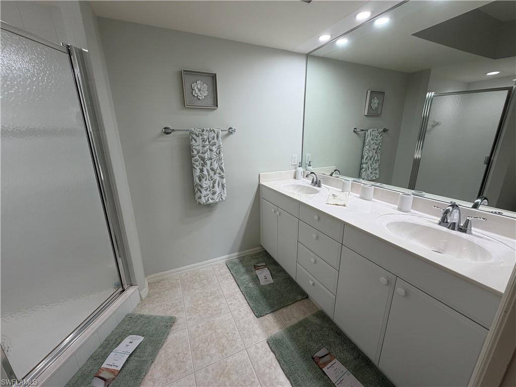 23810 Marbella Bay Road, Unit 102 Estero, FL 34135 - Photo 21 of 26 a bathroom with a double vanity sink and mirror