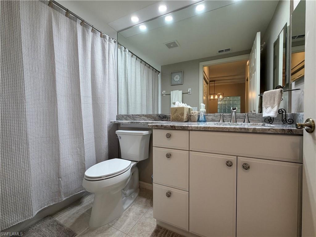 23810 Marbella Bay Road, Unit 102 Estero, FL 34135 - Photo 23 of 26 a bathroom with a granite countertop sink toilet and mirror