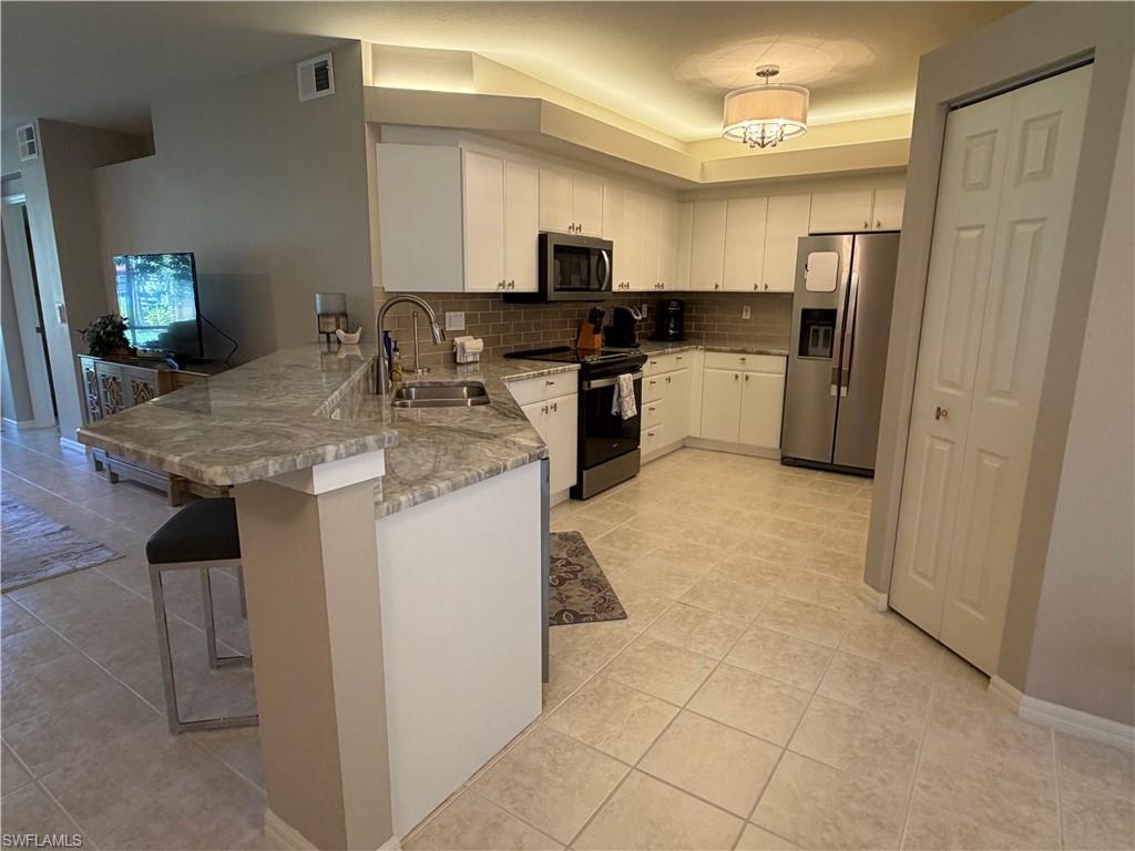23810 Marbella Bay Road, Unit 102 Estero, FL 34135 - Photo 4 of 26 a kitchen with stainless steel appliances granite countertop a sink stove and refrigerator