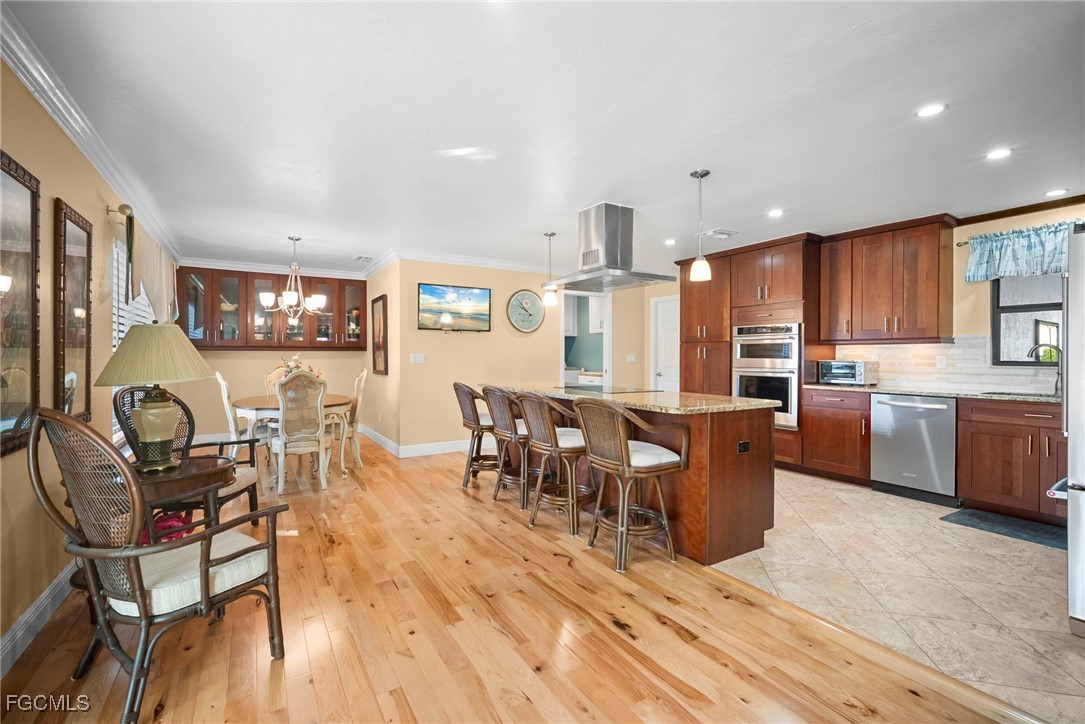 5688 Arvine Circle Fort Myers, FL 33919 - Photo 9 of 39 a open kitchen with stainless steel appliances granite countertop a stove top oven a sink a dining table and chairs with wooden floor