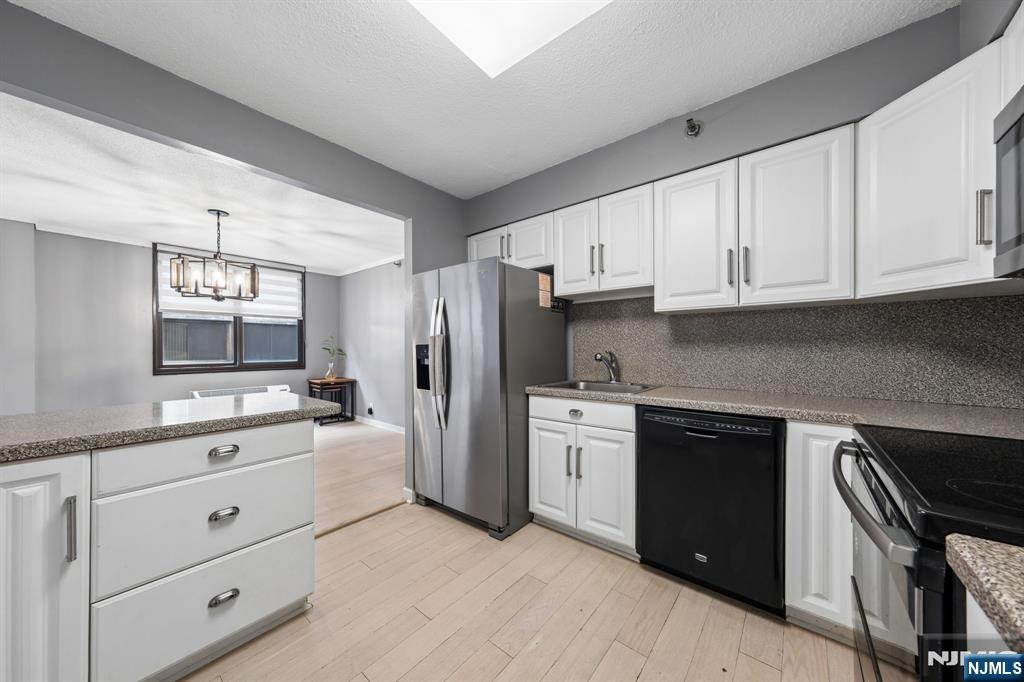 326 Prospect Avenue, Unit 10H Hackensack, NJ 07601 - Photo 4 of 31 a kitchen with white cabinets and stainless steel appliances